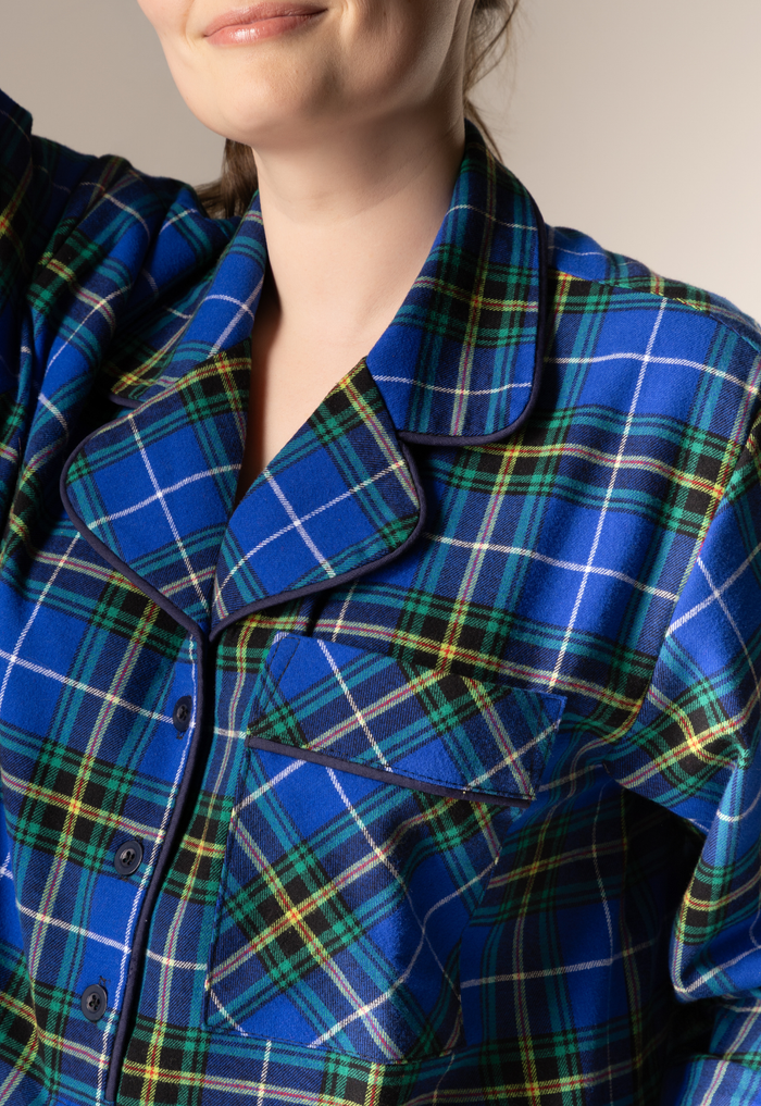 Close-up of a person wearing a blue plaid nightgown with a neutral background