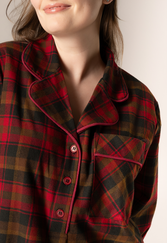 Close-up of a person wearing a maple leaf tartan nightshirt with a neutral background