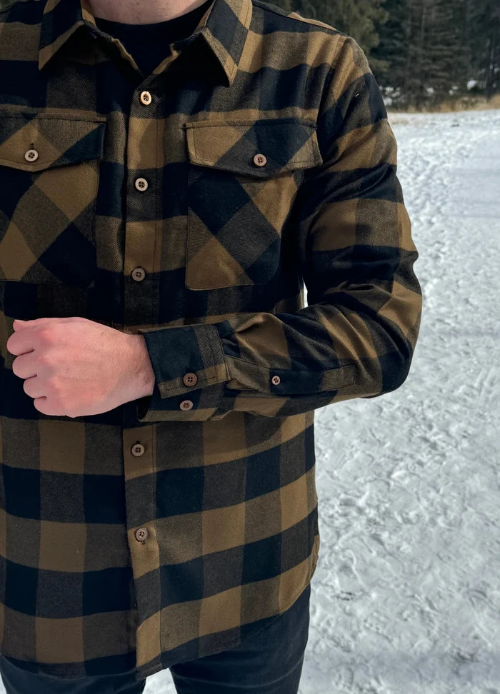 A man wearing a black and brown buffalo check flannel shirt with two flap breast pockets and two button cuff.