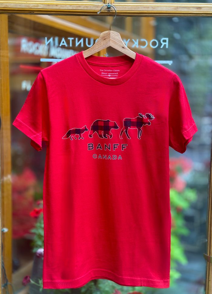 Red t-shirt with 'Banff Canada' design on a hanger in front of a store window.