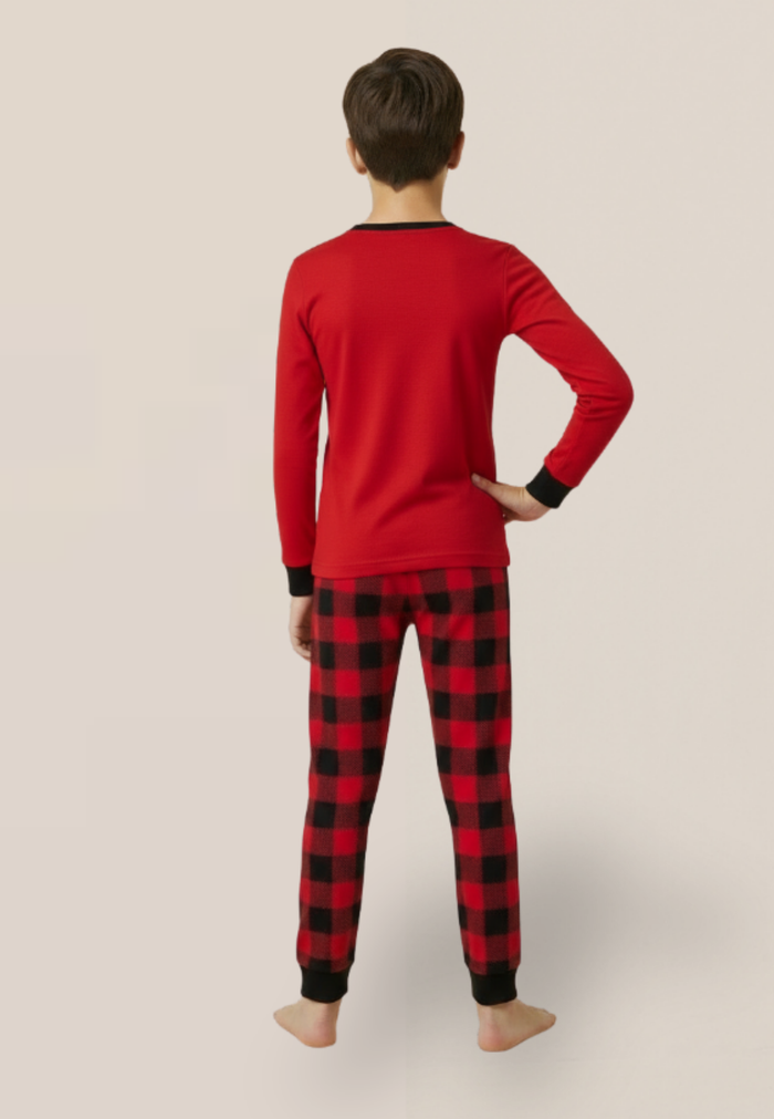 Kid wearing red long-sleeve top and black and red plaid pants on a beige background
