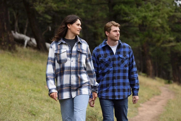 A man wearing a royal blue and black buffalo check padded flannel camping outdoor jacket with jeans.