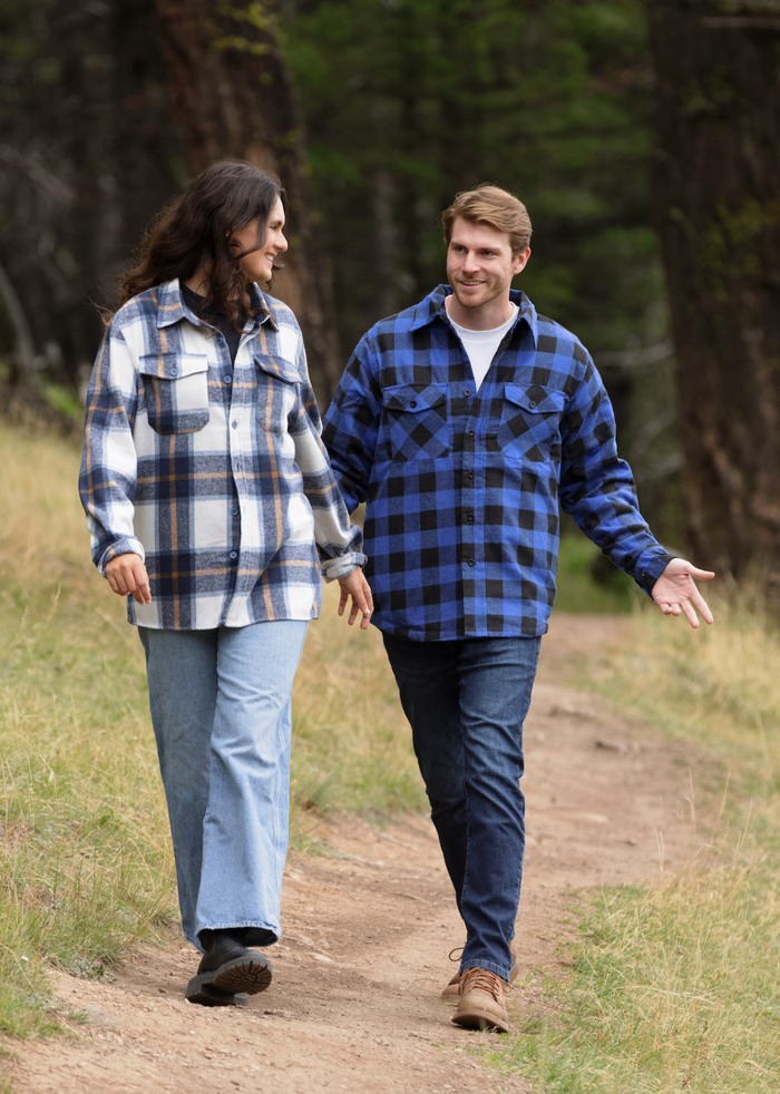A man wearing a royal blue and black buffalo check padded flannel camping outdoor jacket with jeans.